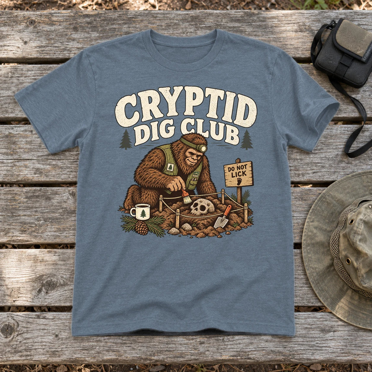 Cryptid Dig Club Graphic Tee on Heather Indigo Everyday Soft Tee